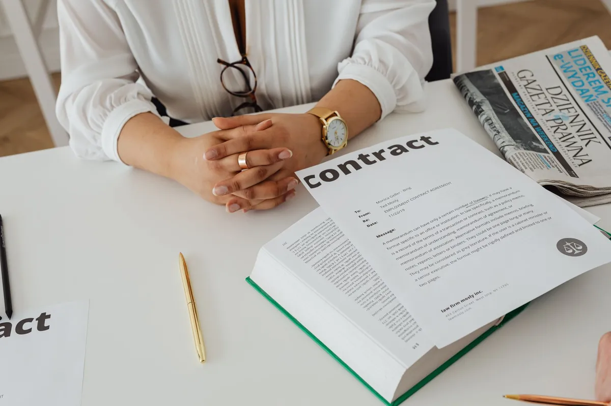 Businesswoman reviewing a contract at a desk with legal documents and a newspaper nearby.