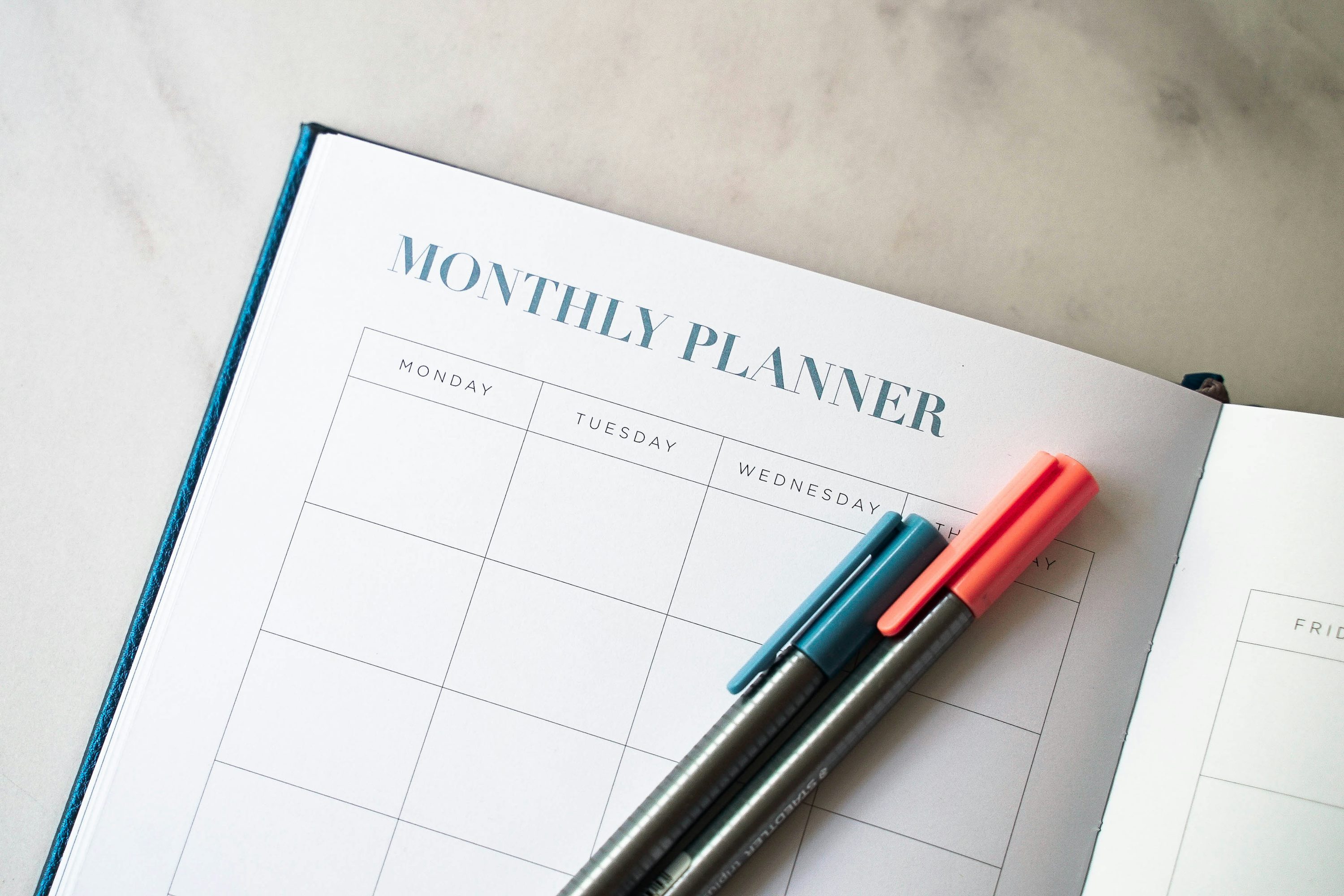 An open monthly planner with coloured pens, illustrating study scheduling.
